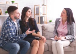 Successful couple therapy. Young grateful spouses talking with marital counselor at office